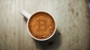 eine bitcoin-münze in einer kaffetasse