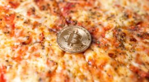 eine bitcoin münze auf einer pizza margaritha