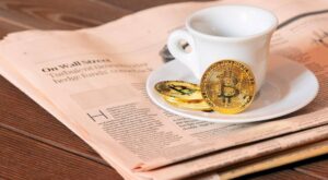 Bitcoin Münze neben Kaffeetasse
