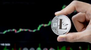 Litecoin-Münze wird vor einem Chart gehalten