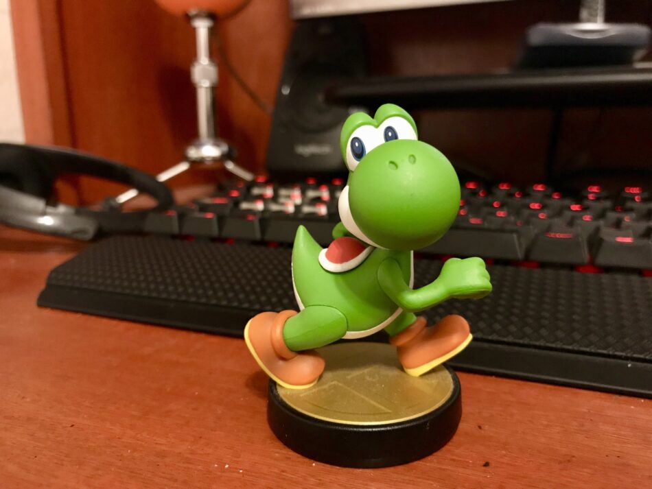 Yoshi auf einem Holzschreibtisch neben einem Desktop-Computer