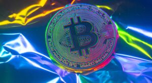 Eine Bitcoin-Münze vor einem bunten Hintergrund.